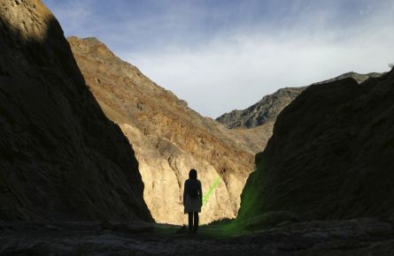 A silhouette of a person standing in Death Valley, holding a green light saber.
